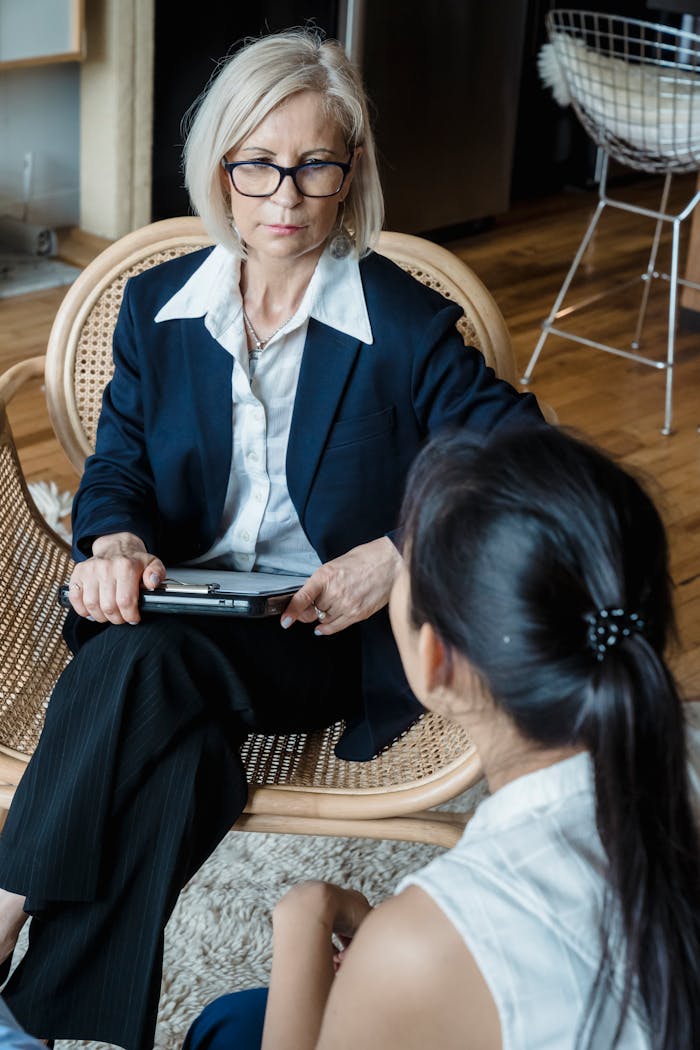 A serious discussion between two businesswomen in a modern office environment.