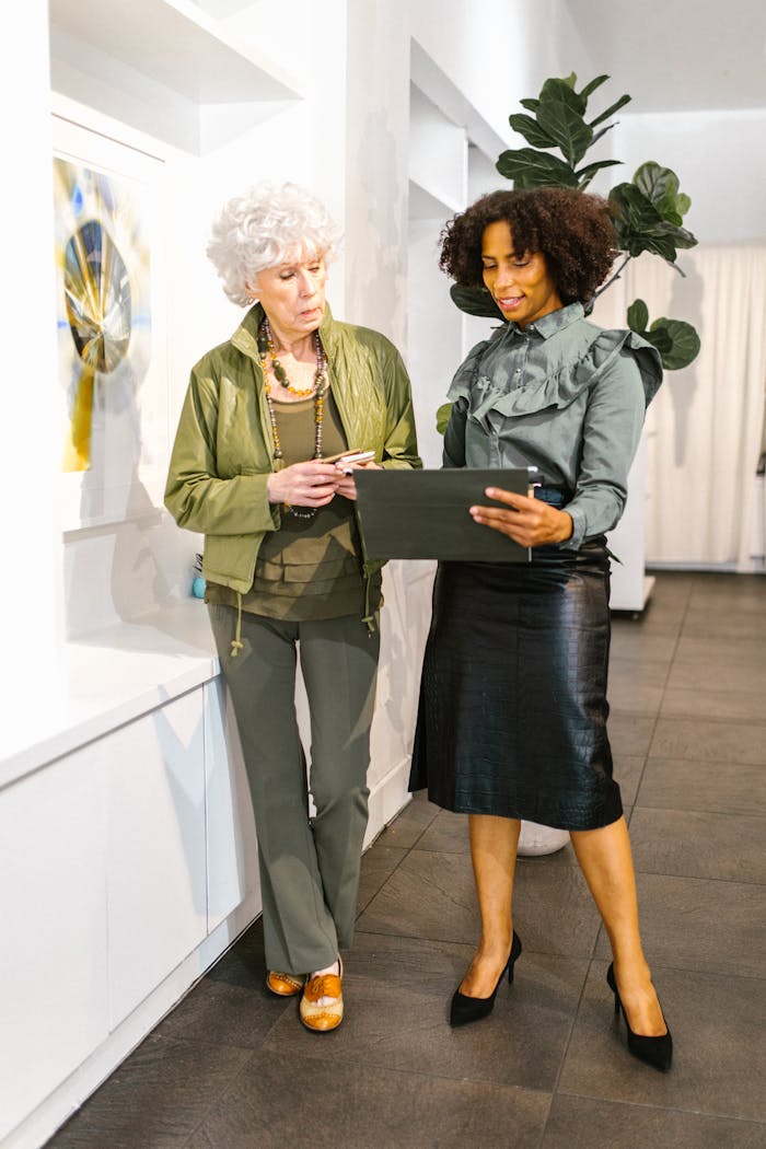 Elegant businesswomen in discussion, reviewing documents in modern office.