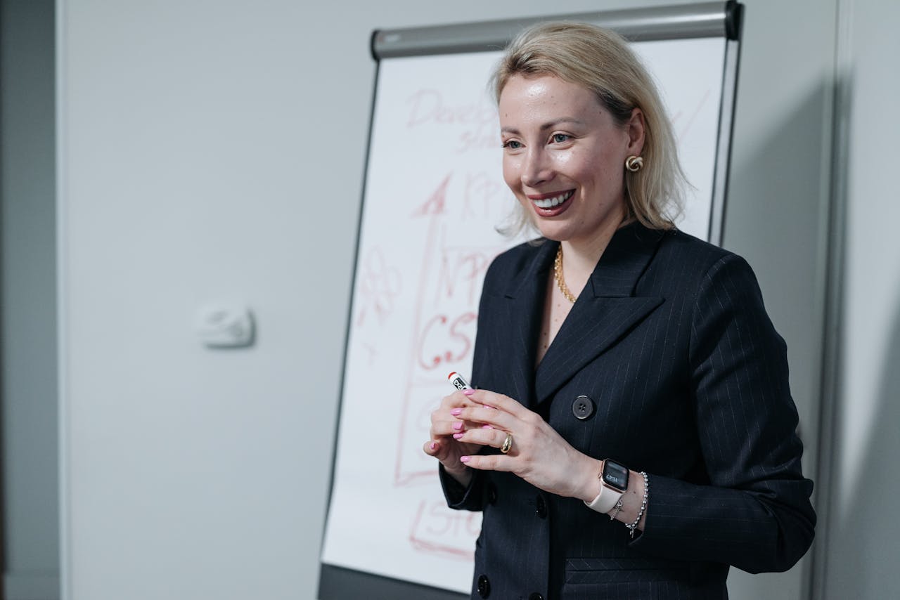 Professional woman giving a presentation in a business setting with a whiteboard.